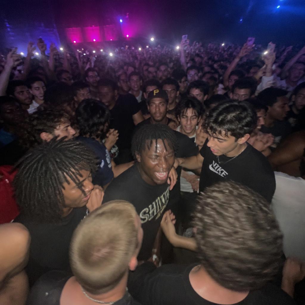 Fans jumping in a circle pit at a rap concert, shot on a phone camera